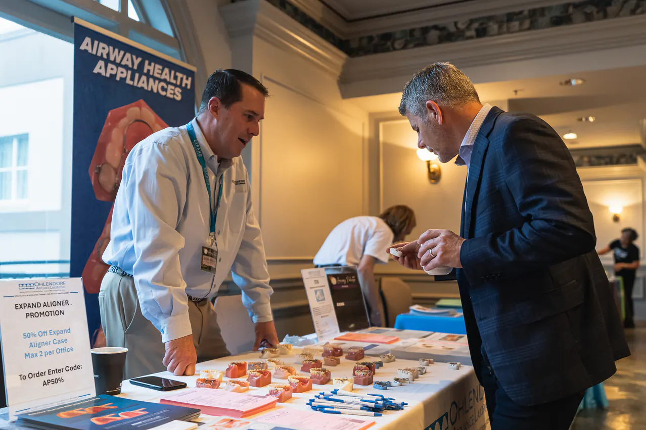 An attendee exploring dental appliances with a vendor at Airway Palooza 2024 in New Orleans